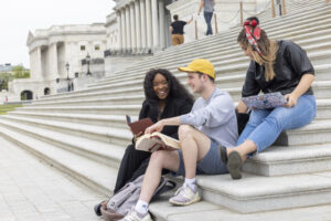 Three students seated on the steps of the U.S. Capitol Building